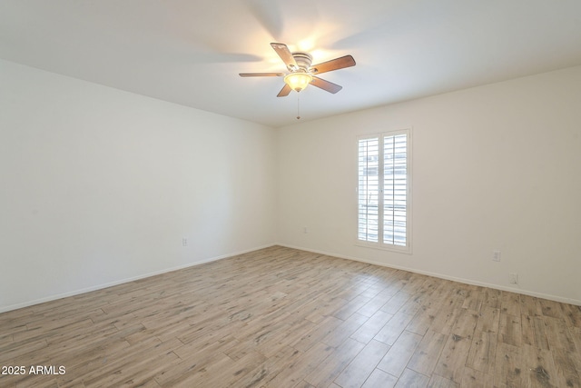 spare room featuring light wood finished floors, baseboards, and a ceiling fan