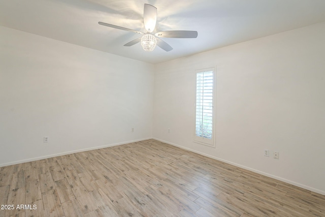 spare room featuring a ceiling fan, light wood-type flooring, and baseboards