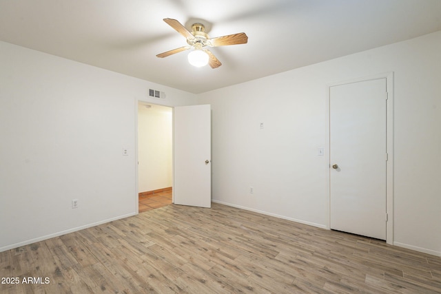 unfurnished bedroom featuring ceiling fan, visible vents, baseboards, and wood finished floors