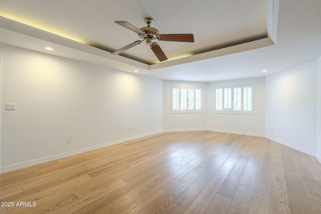 unfurnished room featuring baseboards, a tray ceiling, recessed lighting, light wood-style floors, and a ceiling fan