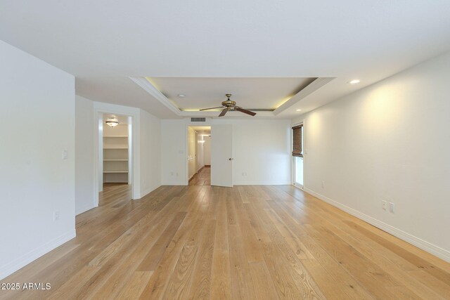 unfurnished room featuring a raised ceiling, a ceiling fan, recessed lighting, light wood-style floors, and baseboards