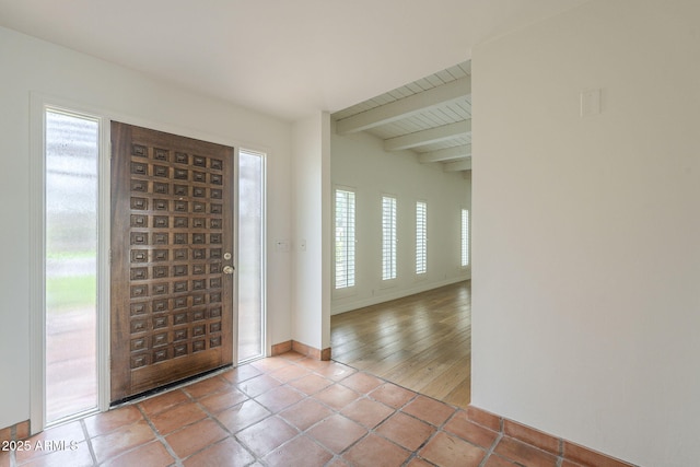 tiled entryway with baseboards and beam ceiling