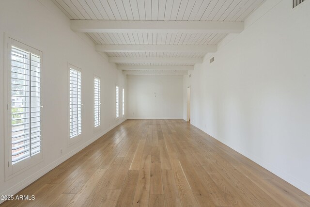 spare room with light wood-type flooring, baseboards, beamed ceiling, and visible vents