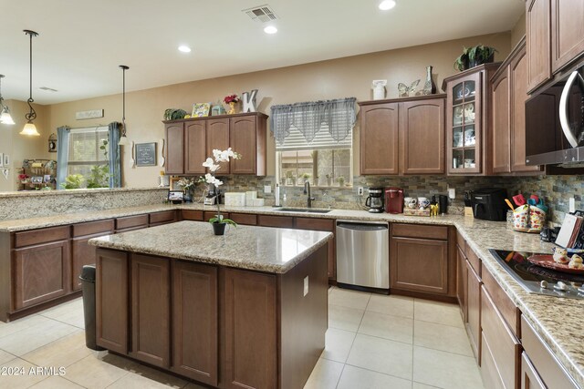 kitchen with tasteful backsplash, light stone counters, stainless steel appliances, hanging light fixtures, and sink