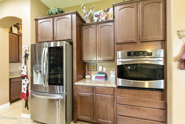 kitchen featuring light stone counters, stainless steel appliances, and light tile patterned floors