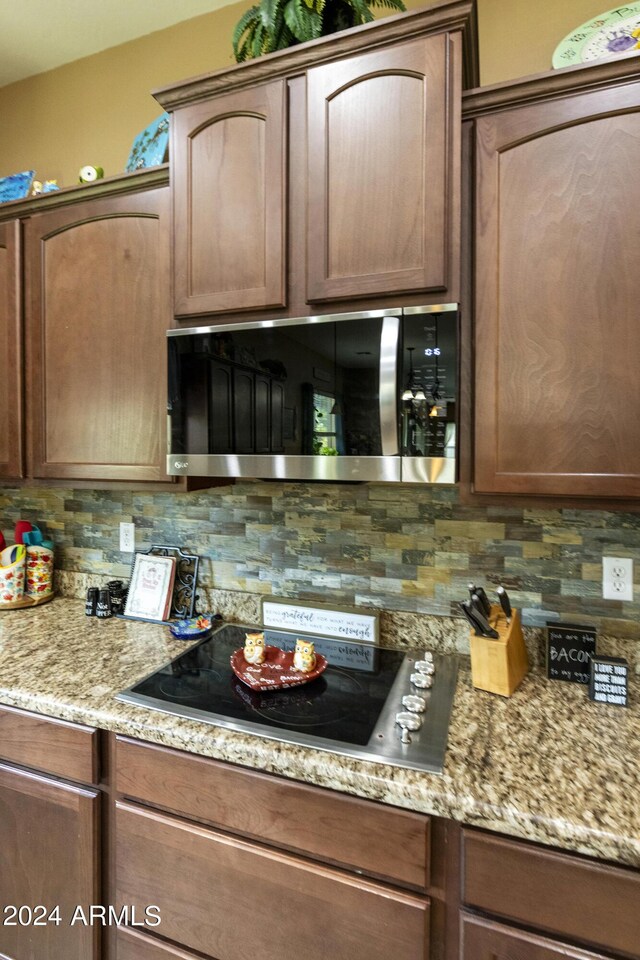 kitchen with black electric cooktop, decorative backsplash, and light stone countertops