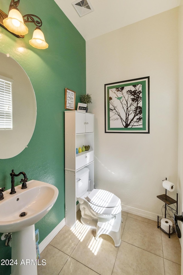 half bath featuring toilet, tile patterned flooring, visible vents, and baseboards