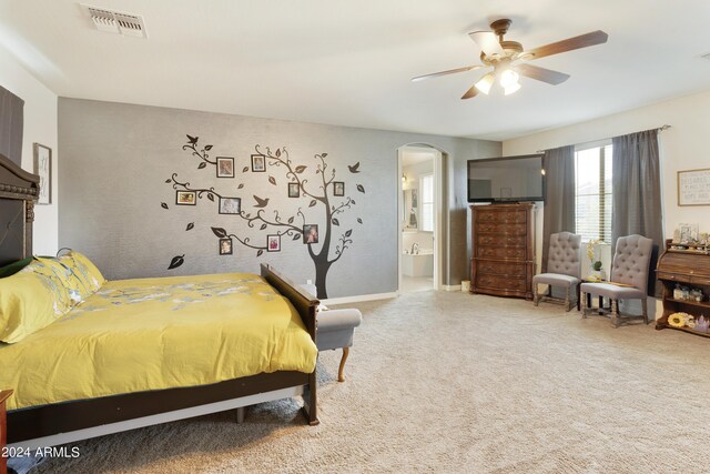 carpeted bedroom with ensuite bath and ceiling fan