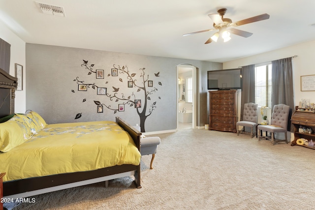 bedroom with arched walkways, ceiling fan, ensuite bathroom, visible vents, and carpet