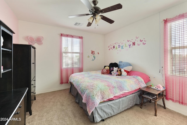 bedroom with light carpet, ceiling fan, visible vents, and baseboards