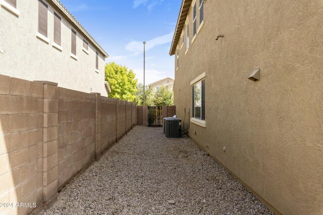 view of side of property featuring fence, cooling unit, and stucco siding