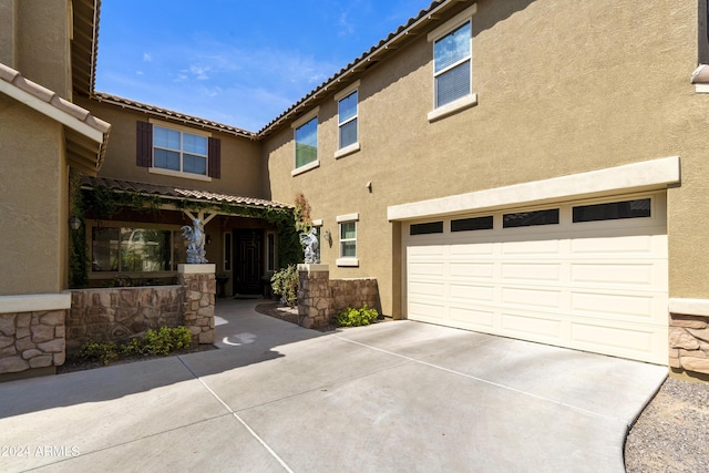 exterior space with an attached garage, a tile roof, concrete driveway, and stucco siding