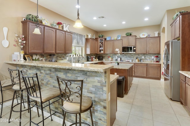 kitchen featuring stainless steel appliances, glass insert cabinets, a peninsula, and a kitchen bar