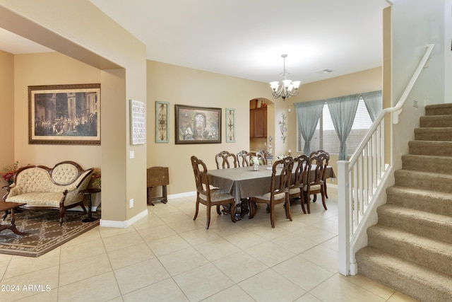 dining room with baseboards, arched walkways, an inviting chandelier, stairs, and light tile patterned flooring