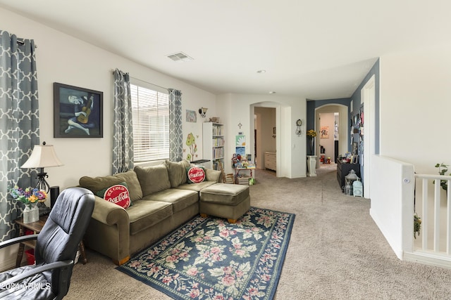 living room featuring arched walkways, carpet flooring, and visible vents