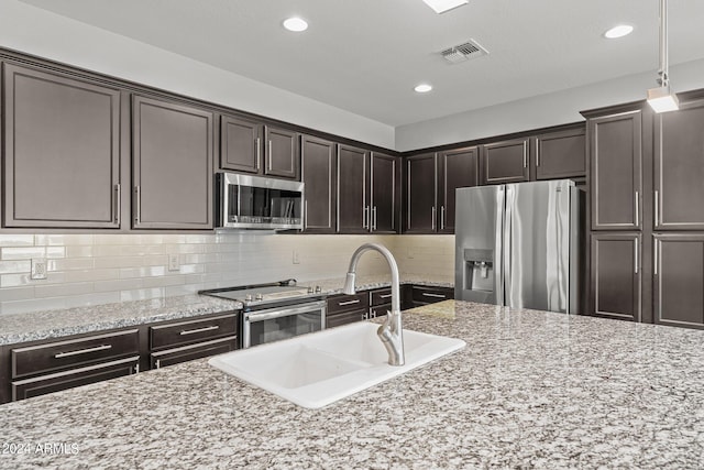 kitchen featuring decorative light fixtures, light stone countertops, and stainless steel appliances