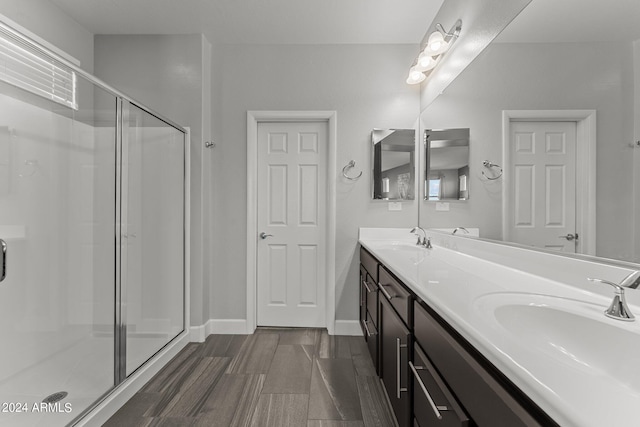 bathroom with a shower with shower door, hardwood / wood-style floors, and vanity