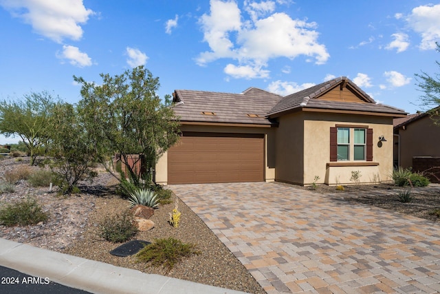 view of front facade with a garage, decorative driveway, a tile roof, and stucco siding