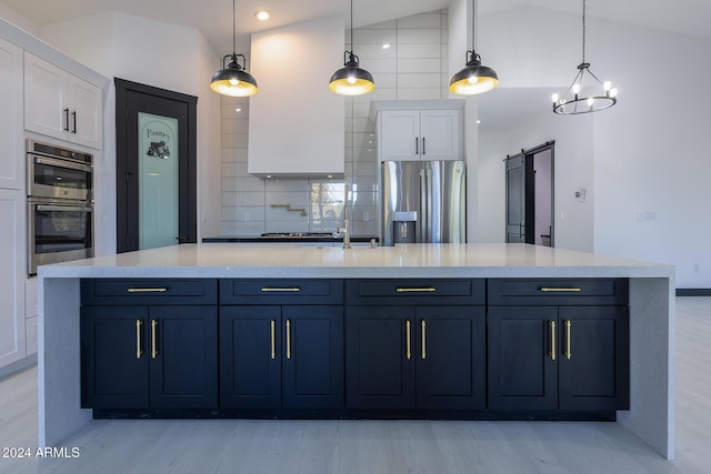 kitchen featuring a barn door, white cabinets, vaulted ceiling, and appliances with stainless steel finishes