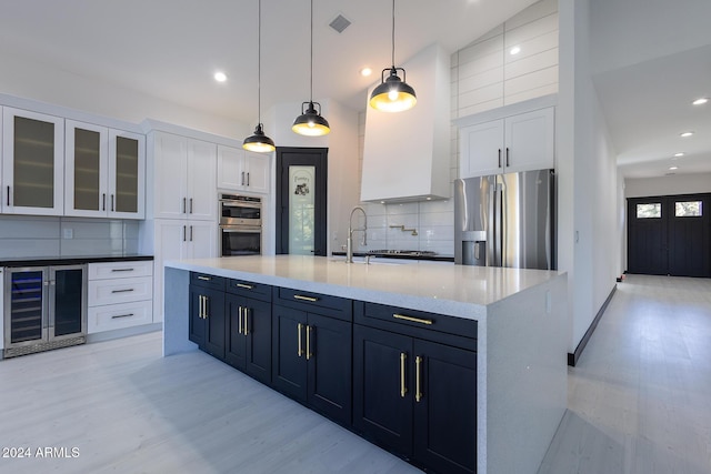 kitchen with hanging light fixtures, light hardwood / wood-style flooring, white cabinetry, stainless steel appliances, and beverage cooler