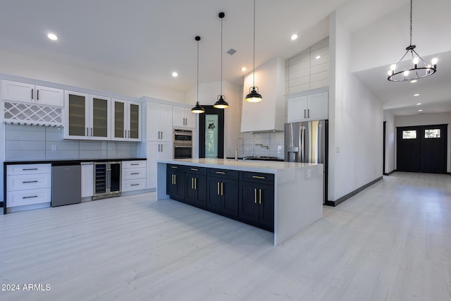 kitchen with backsplash, white cabinetry, an island with sink, and decorative light fixtures