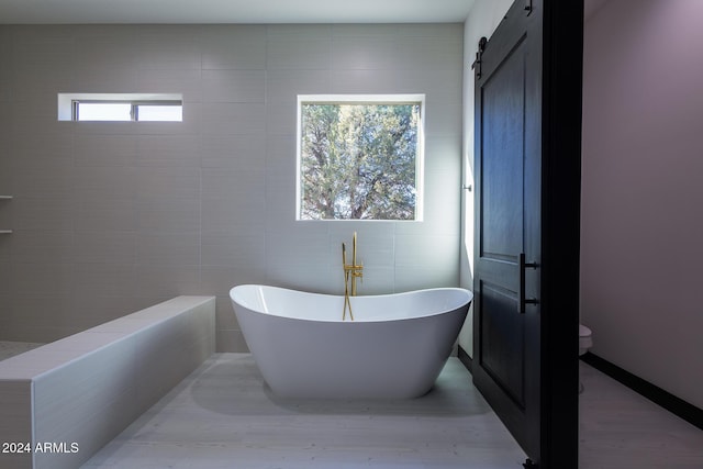 bathroom featuring hardwood / wood-style floors, a bathing tub, and tile walls