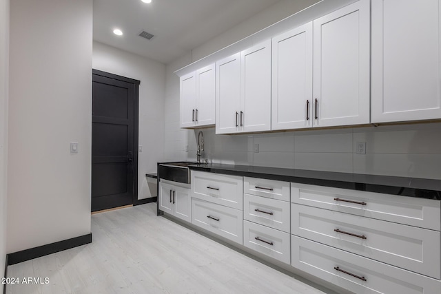 kitchen with light hardwood / wood-style floors, white cabinetry, and sink