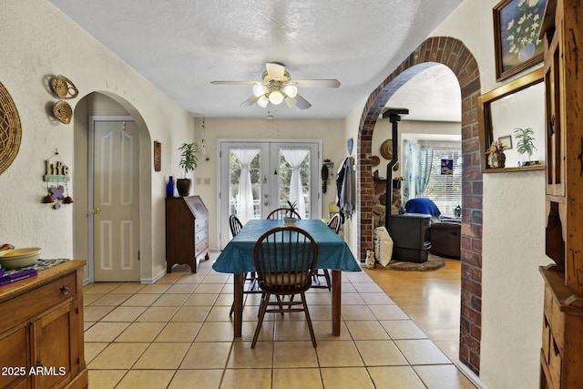 dining space with ceiling fan, light tile patterned floors, a textured ceiling, and french doors