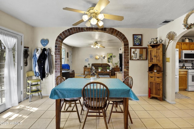 tiled dining area featuring a healthy amount of sunlight, a textured ceiling, and ceiling fan