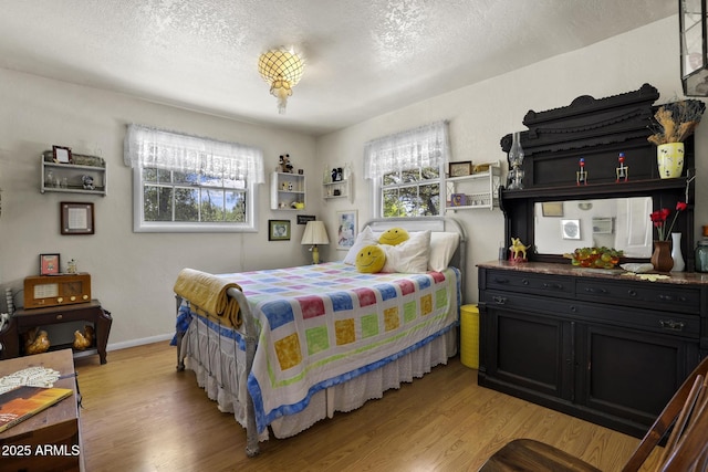 bedroom with a textured ceiling, multiple windows, and light hardwood / wood-style flooring