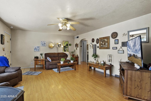 living room with ceiling fan, light hardwood / wood-style flooring, and a textured ceiling