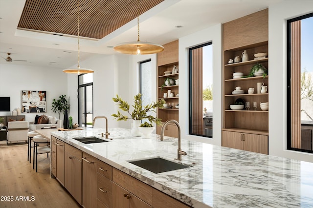 6584 E Gold Dust Ave, Paradise Valley, AZ 85253 - kitchen featuring light stone countertops, light wood-style flooring, pendant lighting, and a sink