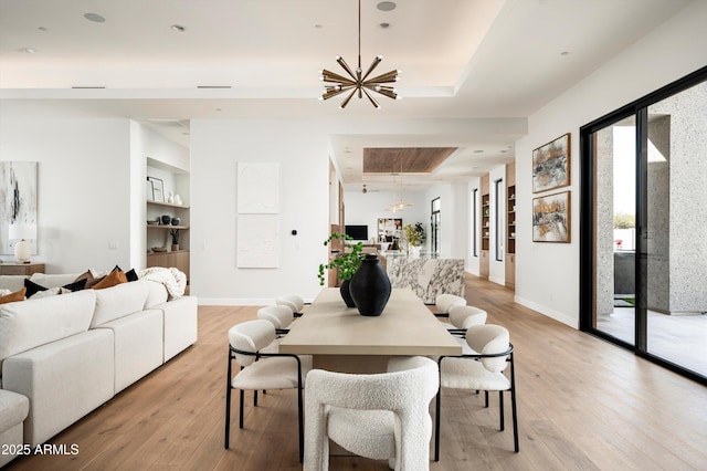6584 E Gold Dust Ave, Paradise Valley, AZ 85253 - dining room with light wood-style floors, built in shelves, an inviting chandelier, a tray ceiling, and baseboards