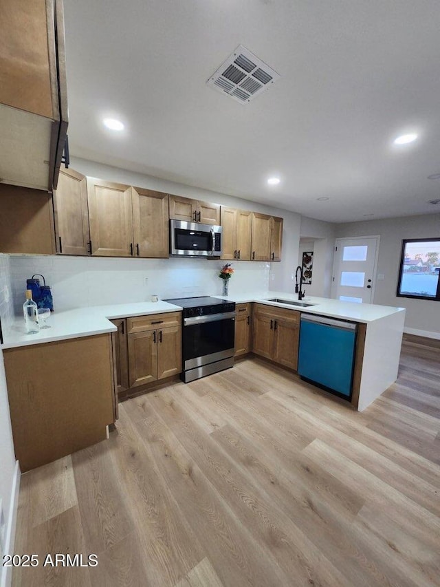 954 E Henry St, Tempe, AZ 85288 - kitchen featuring appliances with stainless steel finishes, a sink, a peninsula, light wood-style flooring, and recessed lighting