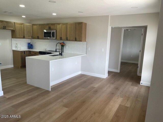 954 E Henry St, Tempe, AZ 85288 - kitchen with stainless steel microwave, a sink, decorative backsplash, a peninsula, and light countertops