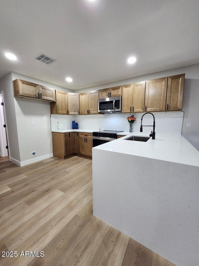 954 E Henry St, Tempe, AZ 85288 - kitchen with appliances with stainless steel finishes, a sink, a peninsula, light wood-style floors, and light countertops