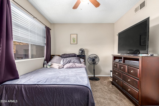 carpeted bedroom featuring ceiling fan and a textured ceiling