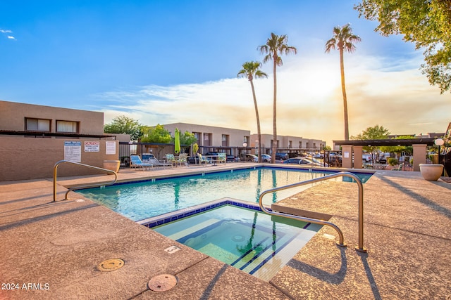 pool at dusk featuring a community hot tub and a patio area