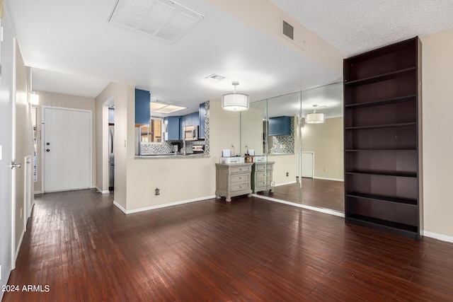 unfurnished living room with a textured ceiling and dark hardwood / wood-style floors