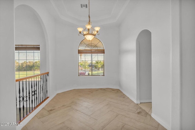 9183 W Shamel Ash Rd, Peoria, AZ 85383 - empty room featuring arched walkways, a chandelier, a tray ceiling, and healthy amount of natural light