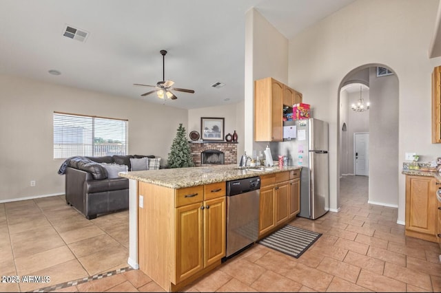 kitchen with arched walkways, stainless steel appliances, visible vents, a ceiling fan, and light stone countertops