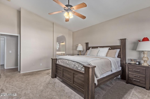 bedroom featuring lofted ceiling, arched walkways, carpet flooring, baseboards, and ensuite bath