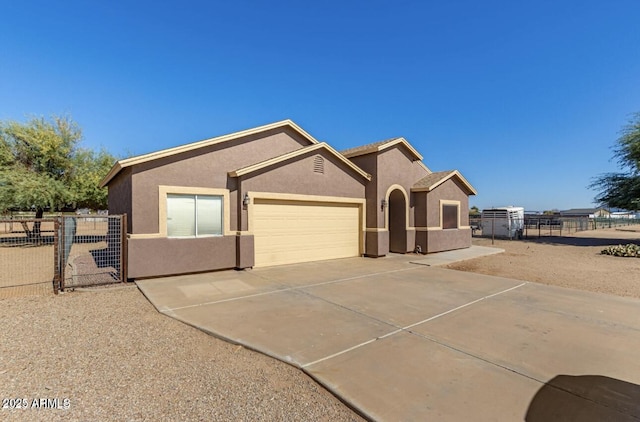 view of front of house with a garage, driveway, fence, and stucco siding