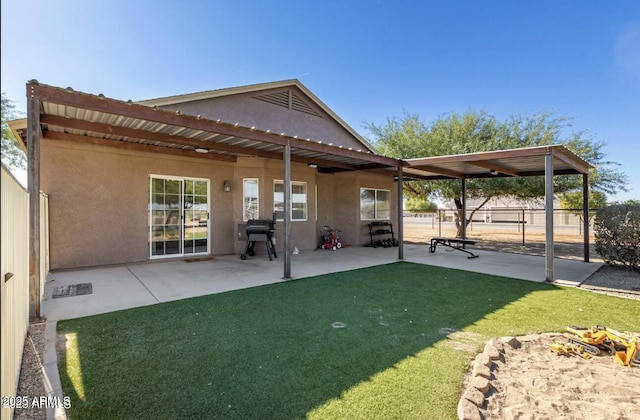 back of house featuring a yard, a patio area, fence, and stucco siding