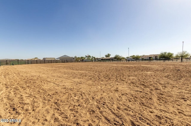 view of yard featuring a rural view, an enclosed area, and fence