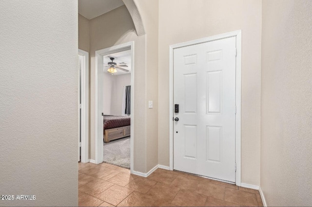 entryway featuring baseboards, arched walkways, and a textured wall