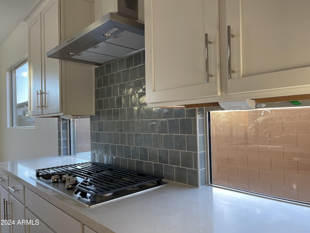 kitchen featuring ventilation hood, tasteful backsplash, white cabinets, and stainless steel gas stovetop