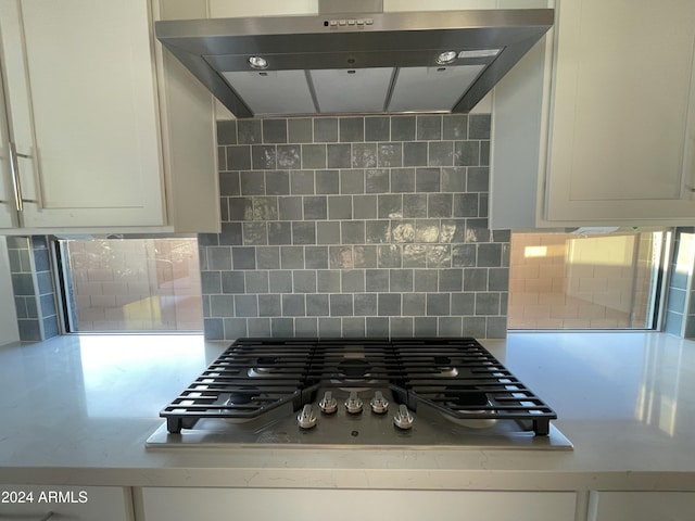 kitchen with wall chimney exhaust hood, stainless steel gas cooktop, and backsplash