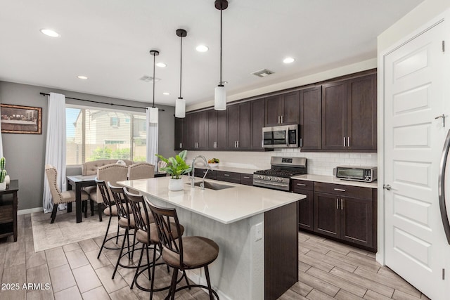 2250 E Palmdale Ln, Gilbert, AZ 85298 - kitchen with stainless steel appliances, a sink, a breakfast bar, dark brown cabinetry, and light countertops