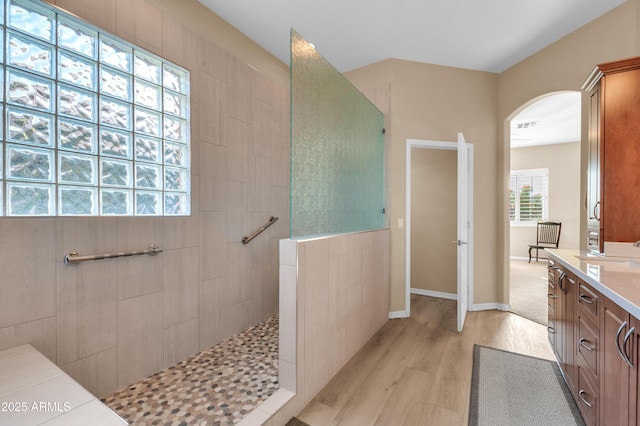 bathroom featuring hardwood / wood-style flooring, tiled shower, and vanity